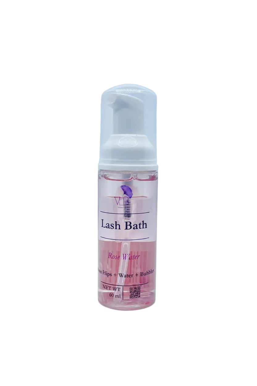 A 60ml bottle of Rose Water Lash Bath with a white pump dispenser, containing pink liquid, set against a light blue textured background.
