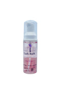 A 60ml bottle of Rose Water Lash Bath with a white pump dispenser, containing pink liquid, set against a light blue textured background.